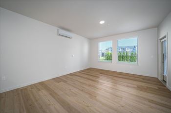 A room with wooden flooring and a window overlooking a green area.
